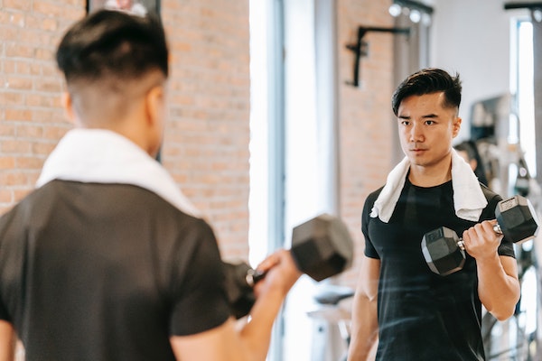A Man Doing Alternating Dumbbell Curls To Reduce Belly Fat