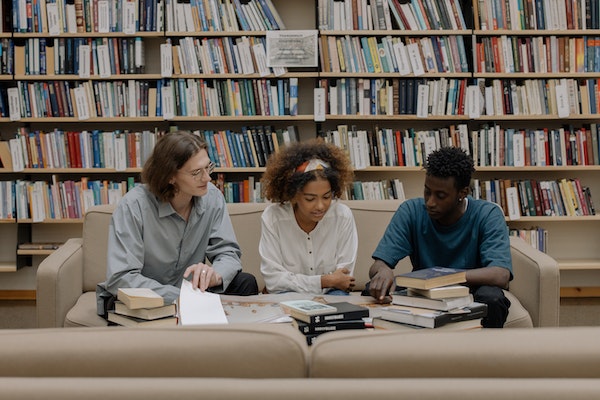 A Group Of Friends Reading Books At The Library