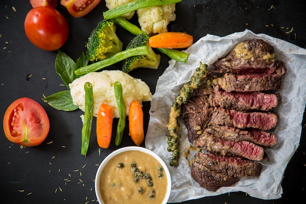 A Steak With Side Sauce And Vegetables