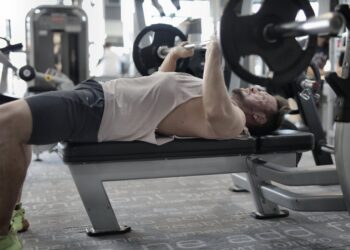strong sportsman working out on bench in modern gym