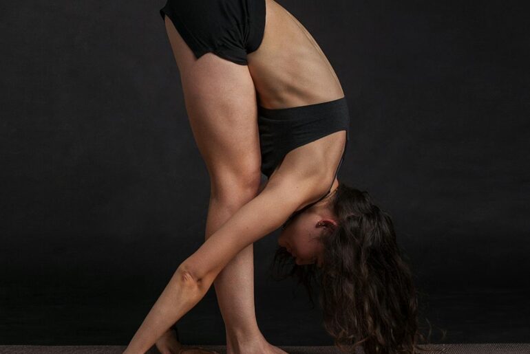 woman wearing black sports bra reaching floor while standing